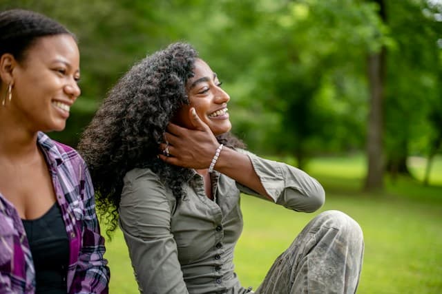 Two friends laughing together outdoors in a green park