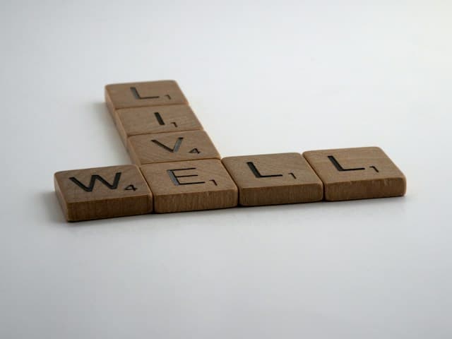 Wooden letter tiles spelling live and well on a light surface